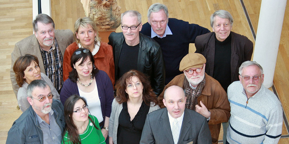 Foto: Die 13 ausstellenden Künstler des Wittener Künstlerbundes, Uwe Träris, Geschäftsführer der Stadtwerke Witten (grauer Anzug, rechts) und Dr. Gert Buhren, Vorsitzender des Wittener Künstlerbundes (links oben). Im Hintergrund Skulptur — von Martin Sprave, „Poseidon“ (Foto: Manuela Sommerrey / Stadtwerke Witten).